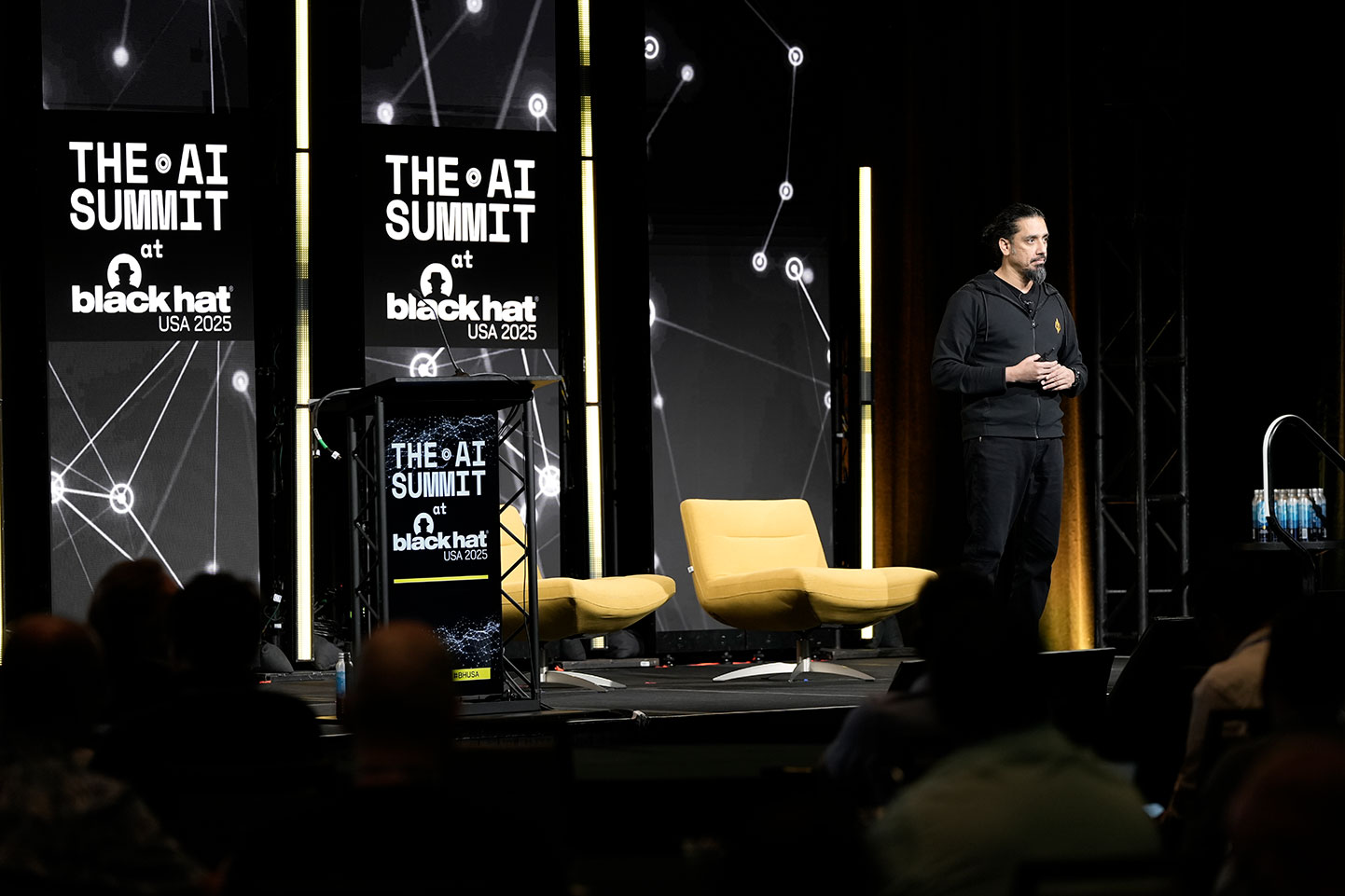 A speaker addresses a crowd on stage at the AI Summit at Black Hat USA 2025.